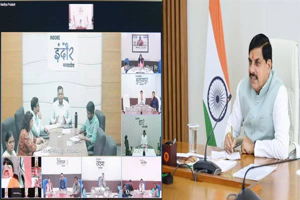 मुख्यमंत्री समत्व भवन में झंडों के पास बैठे हैं; स्क्रीन पर इंदौर और अन्य जिलों के अधिकारी वीसी में दिख रहे हैं